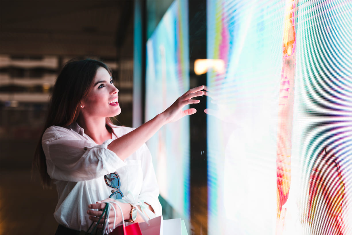 mujer impresionada al mirar el panel LED publicitario