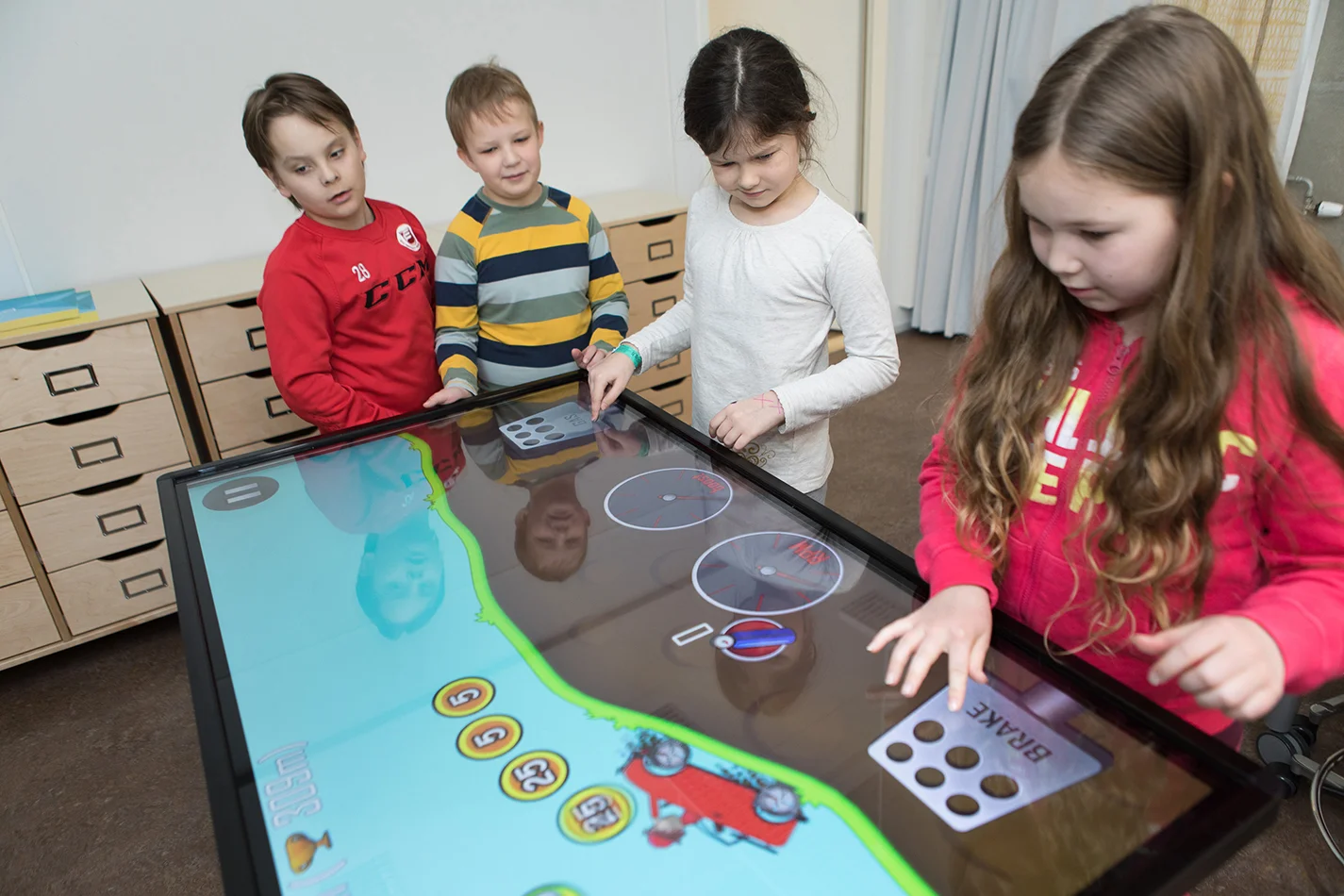 Niños interactuando con la pantalla interactiva y jugando juegos educativos